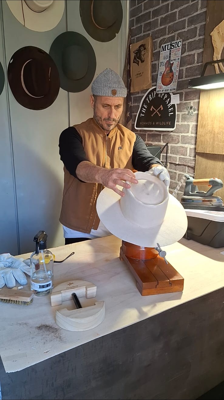 Artesano sosteniendo un sombrero de ala ancha sobre la horma de madera
