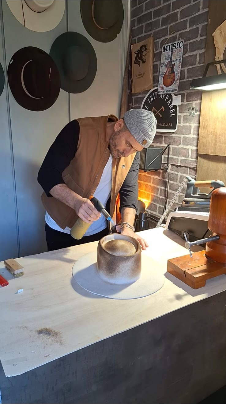 Artesano aplicando fuego sobre la copa de un sombrero en el taller